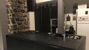 Eine moderne Küche mit schwarzem Arbeitsplatz, einem Gasherd, einer Spüle und einer Steinwand.