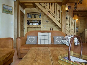 A wooden interior with a sofa, a wooden table, and a staircase.