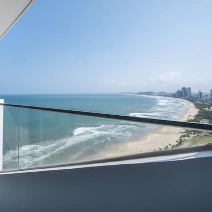 A balcony with a view of the beach and ocean.