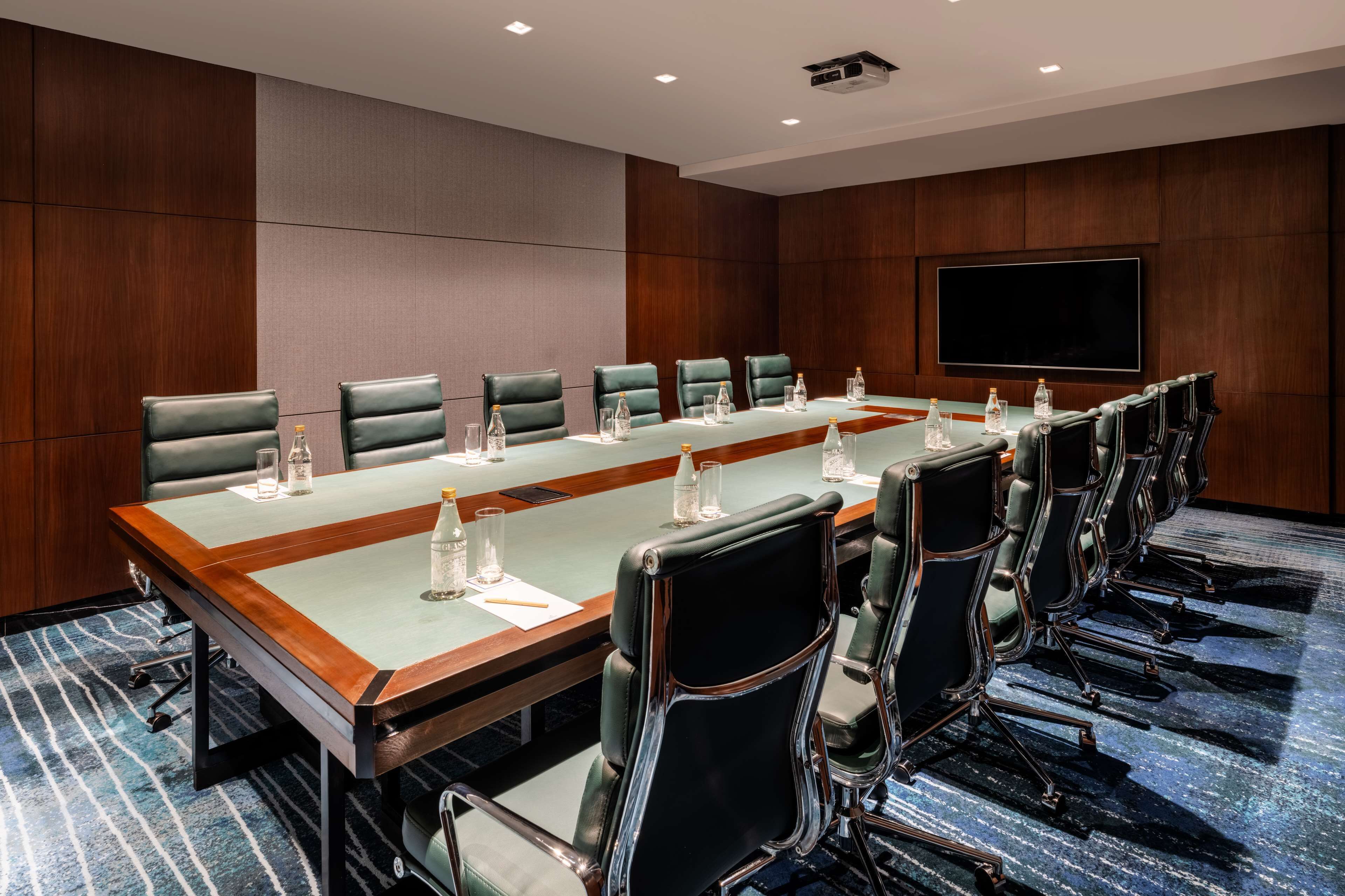 Une salle de conférence avec une longue table, de nombreuses chaises et un grand écran.