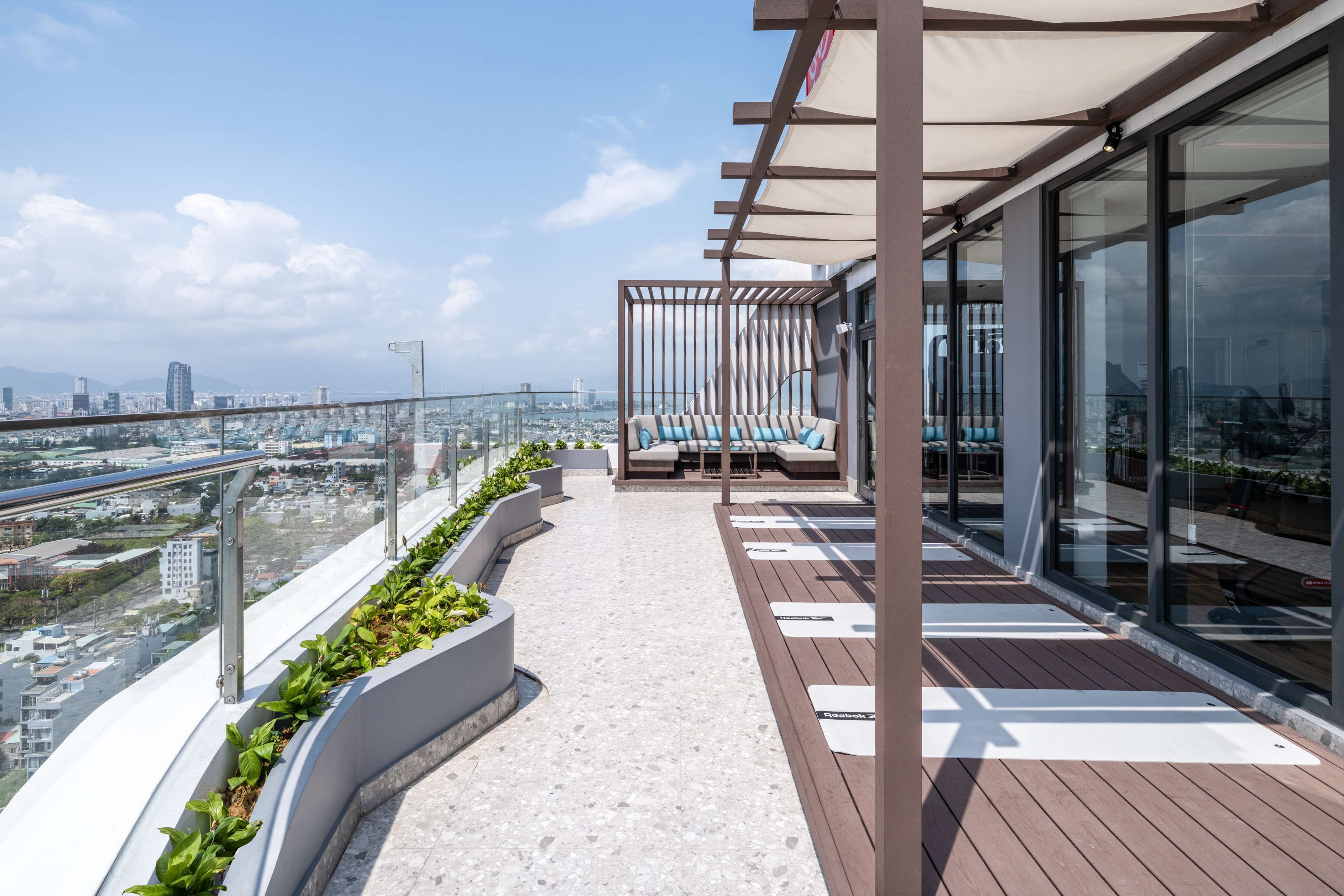 Eine moderne Dachterrasse mit Sitzgelegenheit, Glasgeländern und Blick auf die Stadt.