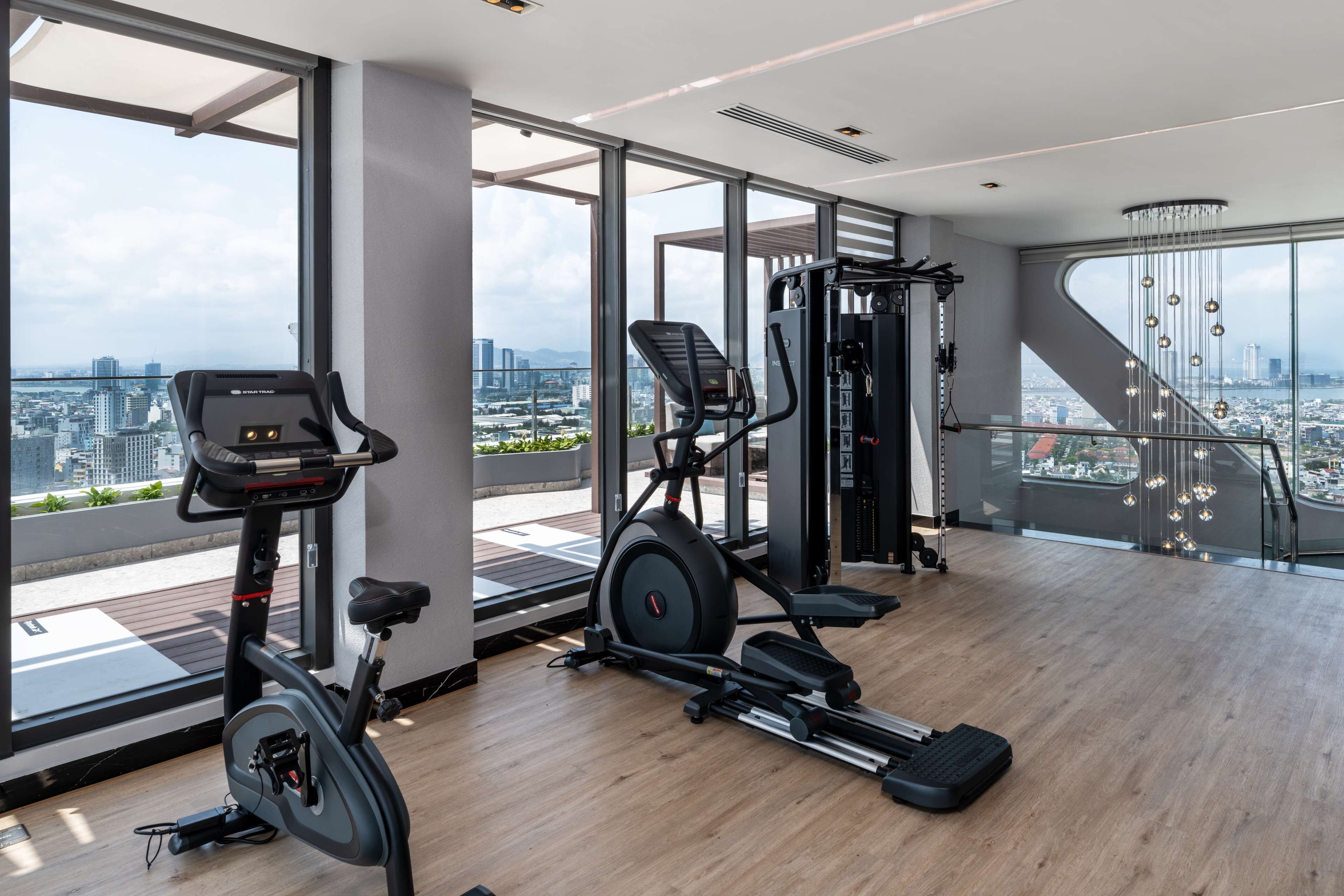 Een moderne sportschool met stadszicht, uitgerust met cardioapparatuur en gewichtstrainingsapparatuur.