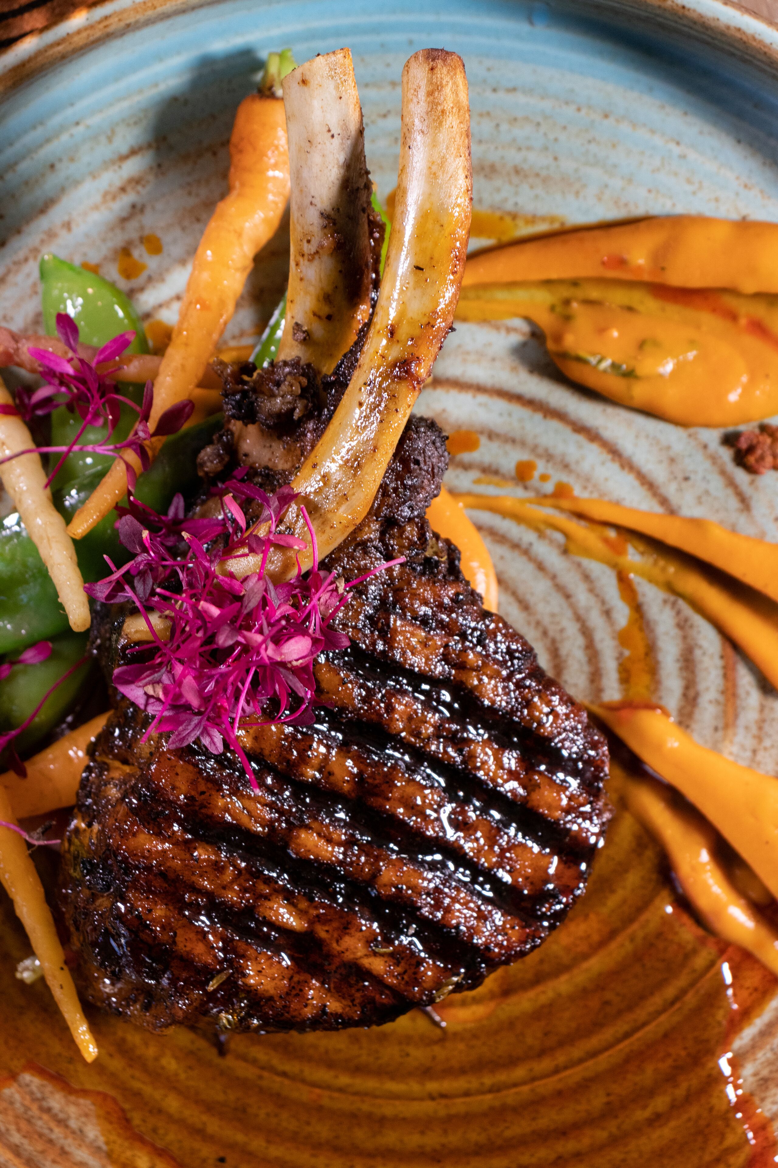 A plate with a grilled steak, asparagus, and a decorative garnish.
