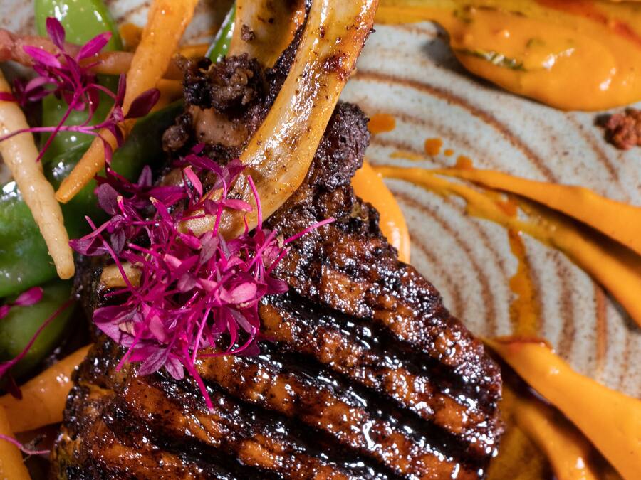 A plate with a grilled steak, asparagus, and a decorative garnish.