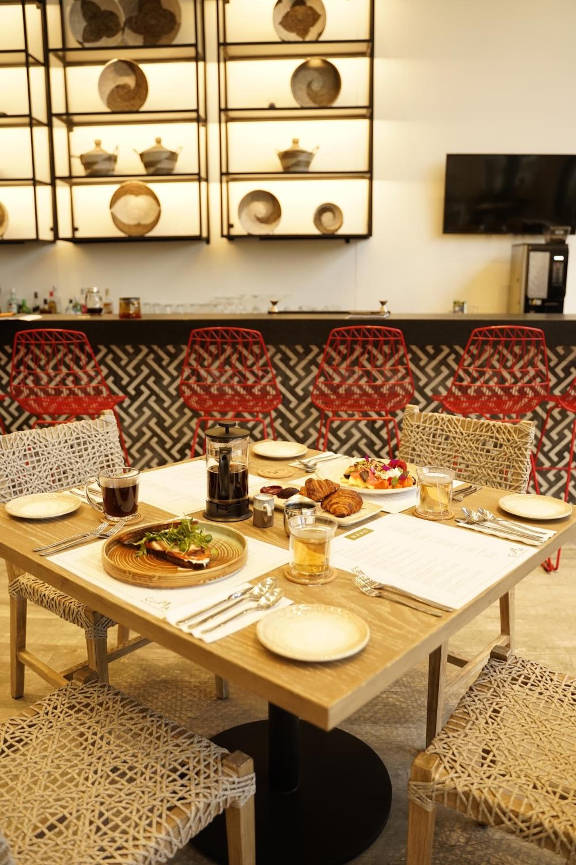 Un comedor con una mesa de madera dispuesta para una comida, rodeado de sillas de mimbre.