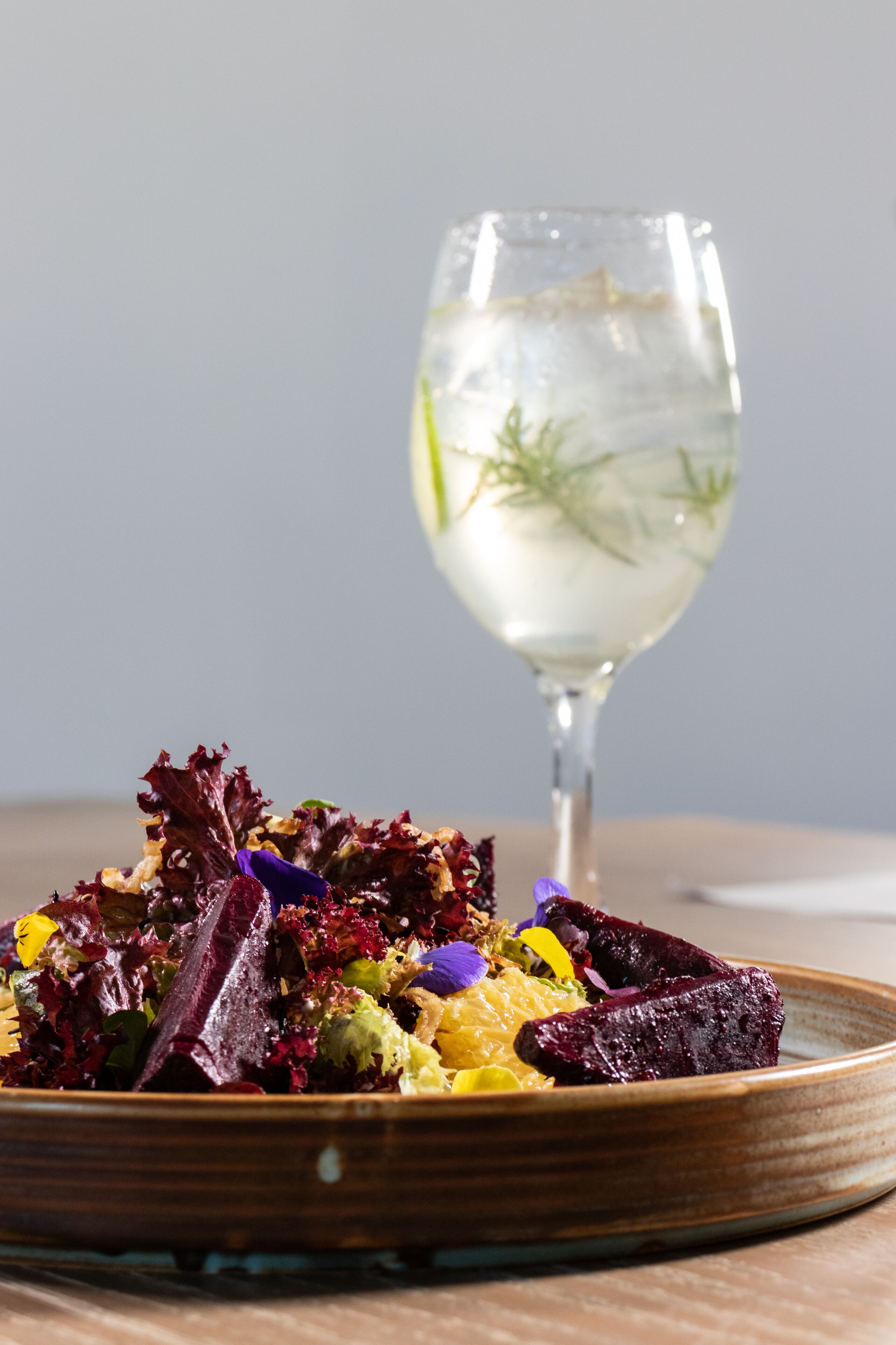 A plate of colorful salad with a glass of water in the background.