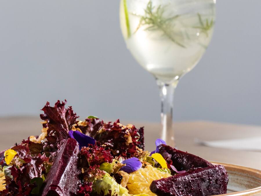 A plate of colorful salad with a glass of water in the background.