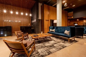 Un vestíbulo moderno con una pared de madera, un sofá azul, sillones de cuero y una mesa de centro.