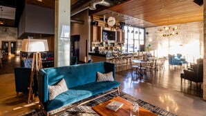 A modern interior with a blue sofa, wooden coffee table, and a bar area. - TRYP by Wyndham San Luis Potosi Hotel & Suites (San Luis Potosi)
