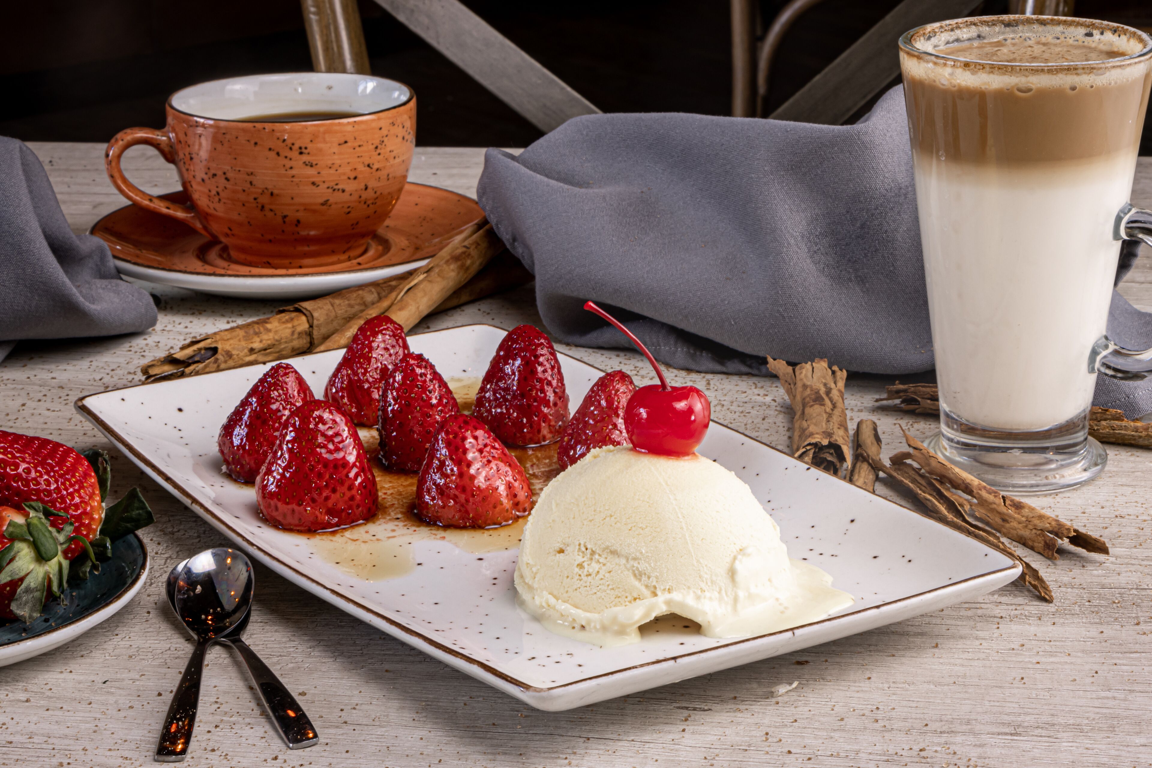 A dessert plate with strawberries, a scoop of ice cream, and a cherry on top.