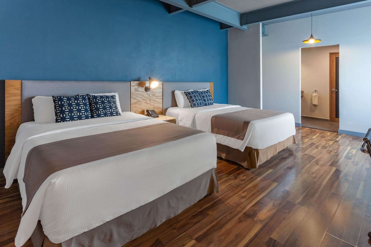 Une chambre d’hôtel avec deux lits, un plancher en bois et un mur bleu.