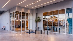 A modern lobby with glass doors, a potted plant, and a seating area. - TRYP by Wyndham San Luis Potosi Hotel & Suites (San Luis Potosi)