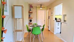 A dining area with a table set for four, green chairs, and a white cabinet to the left.