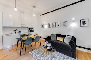 Un espace de vie moderne comprenant un coin repas, une cuisine et un canapé en cuir noir agrémenté de coussins.