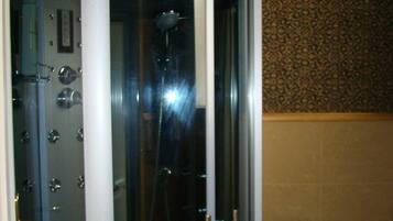 A glass-enclosed shower stall with a toilet to the right.