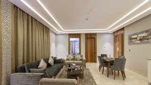 A modern living room with a sofa, armchairs, a coffee table, and a dining area with chairs and a table.
