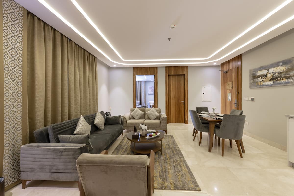 A modern living room with a sofa, armchairs, a coffee table, and a dining area with chairs and a table.