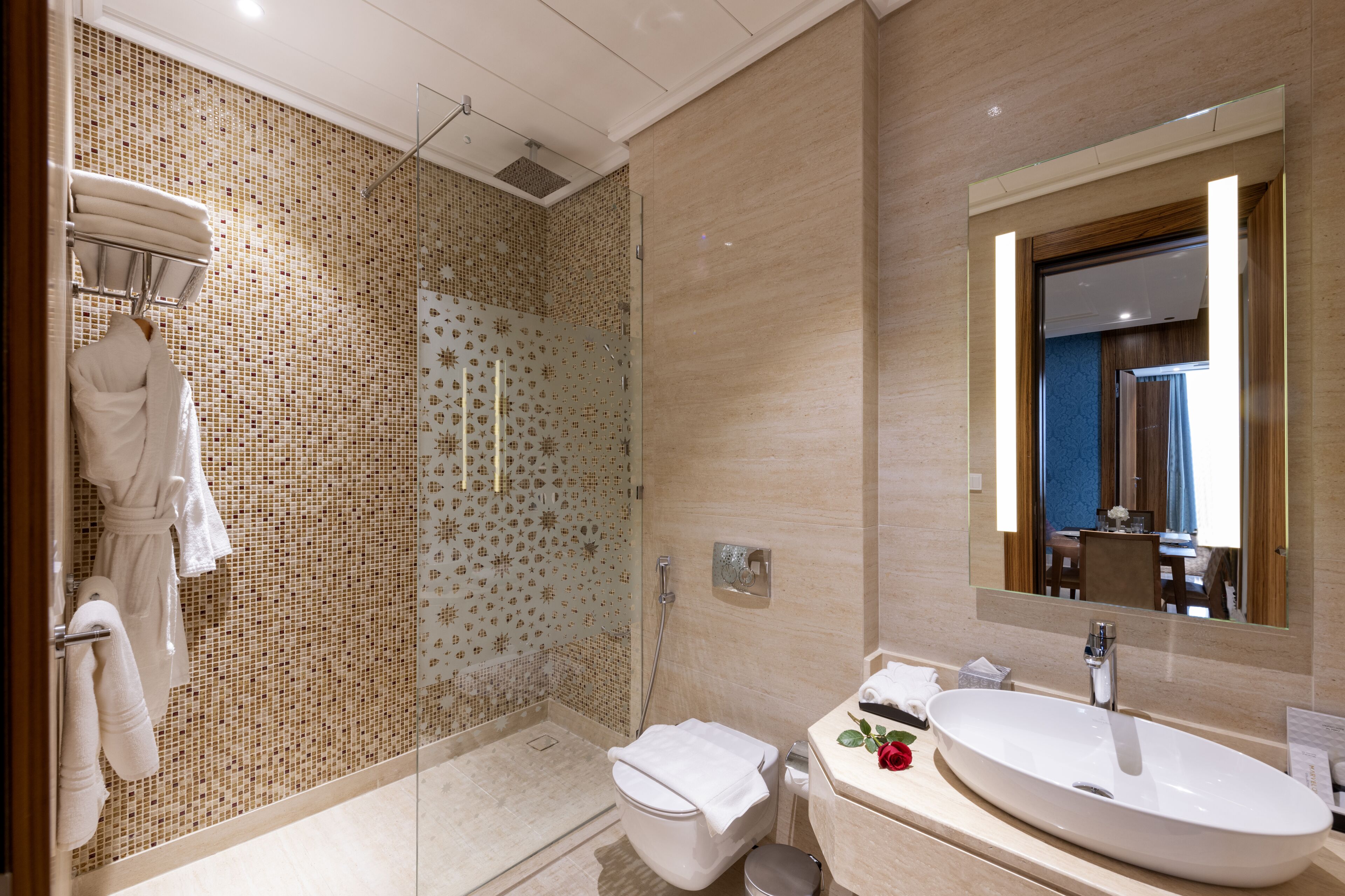 A modern bathroom with a glass-enclosed shower, a white sink, and a large mirror.