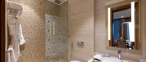 A modern bathroom with a glass-enclosed shower, a white sink, and a large mirror.