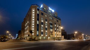 A modern hotel with a prominent sign, multiple floors, and a well-lit facade.