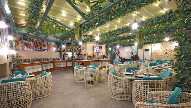 A restaurant with wicker furniture, a bar area, and hanging plants.