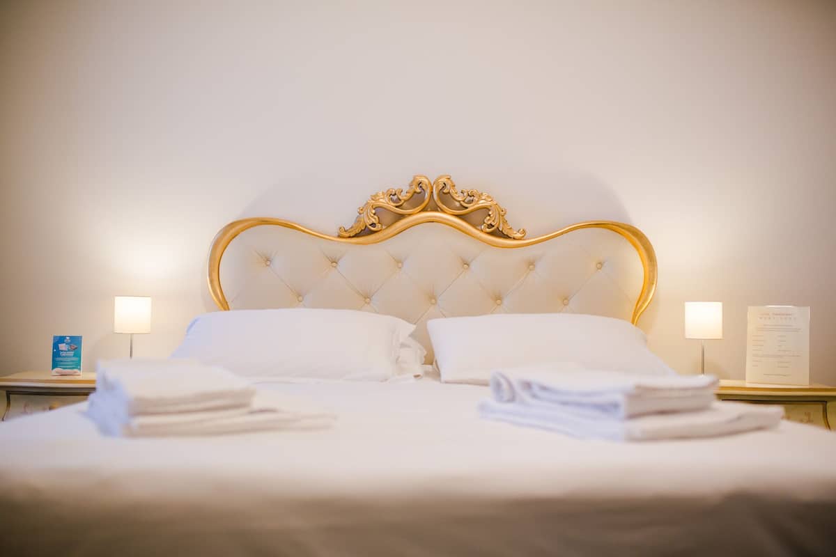 A neatly made bed with a tufted headboard and two bedside lamps.