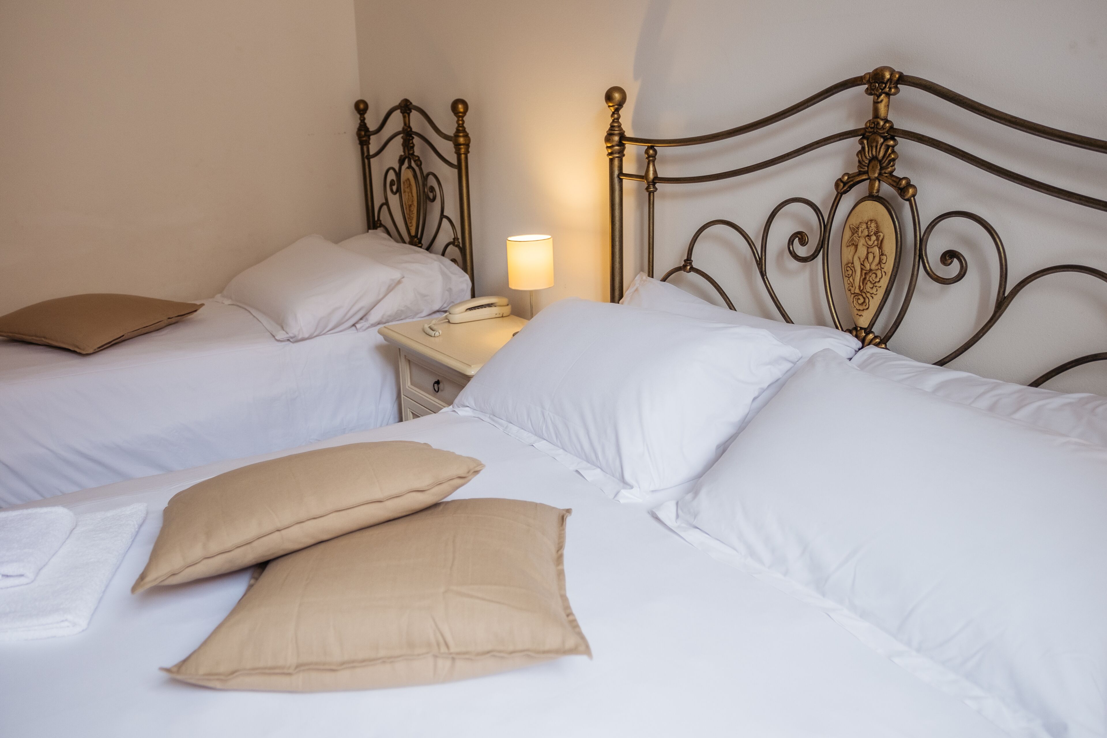 A double bed with a nightstand, a lamp, and two pillows.