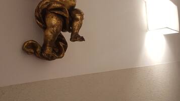 A wall-mounted golden angel sculpture with a light fixture to its right.
