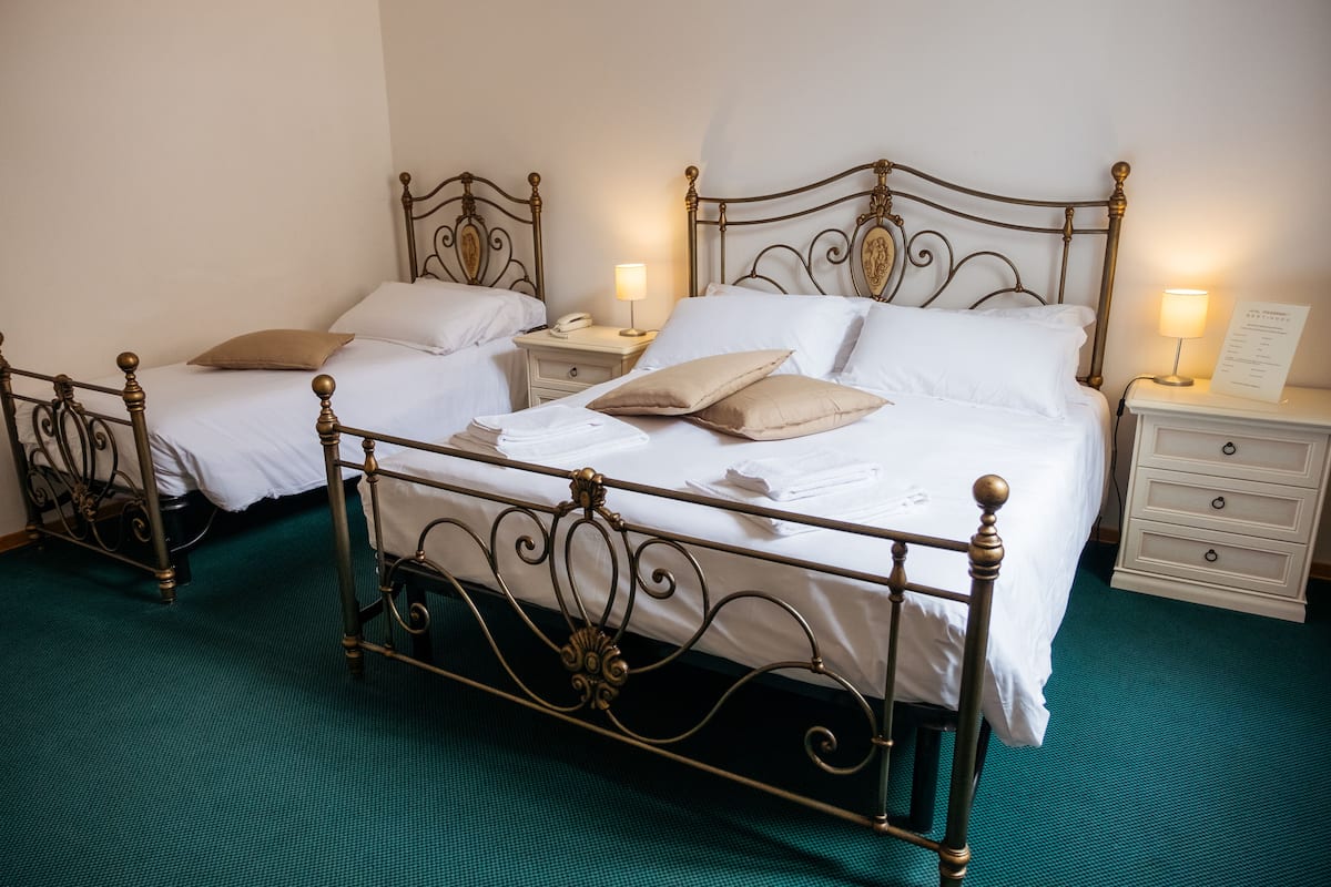A room with two beds, each with a nightstand, a lamp, and a sign on the nightstand.