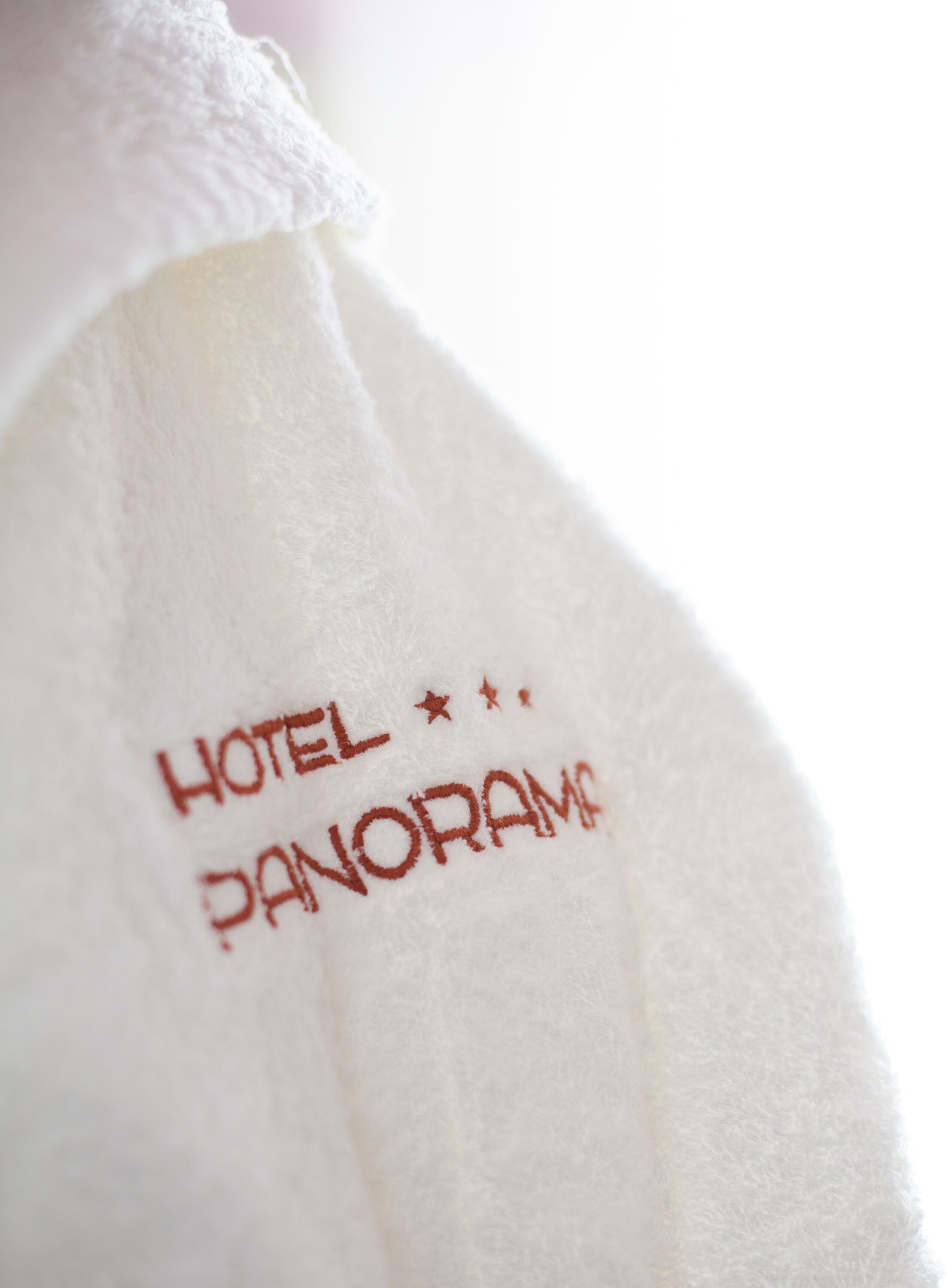 A white towel with embroidered text reading "HOTEL PANORAMA".
