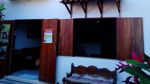 A building with a wooden porch, a bench, and a sign indicating a tour. - Pousada Fantasia (Paraty)