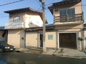 A two-story building with a balcony on the upper floor, a sign indicating a hostel, and a parked car in front. - Pousada Fantasia (Paraty)