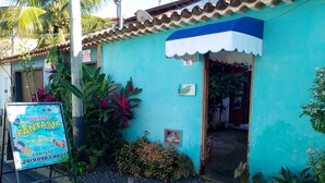 A small, turquoise building with a blue awning and a signboard advertising a business. - Pousada Fantasia (Paraty)