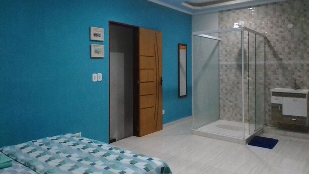 A bedroom with a bed, a door, a shower, and a bathroom. - Pousada Fantasia (Paraty)