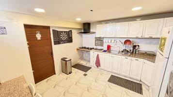A kitchen with white cabinets, a stove, a sink, and a trash bin.