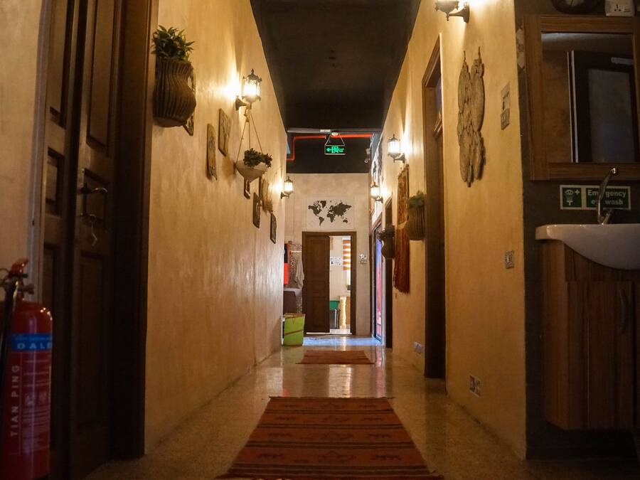 A hallway with a fire extinguisher, a world map, and a sink with an emergency wash sign.