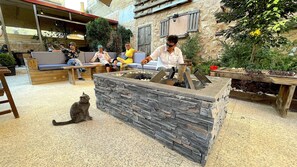 An outdoor seating area with stone walls and a fire pit. - Carob Hostel (Amman)