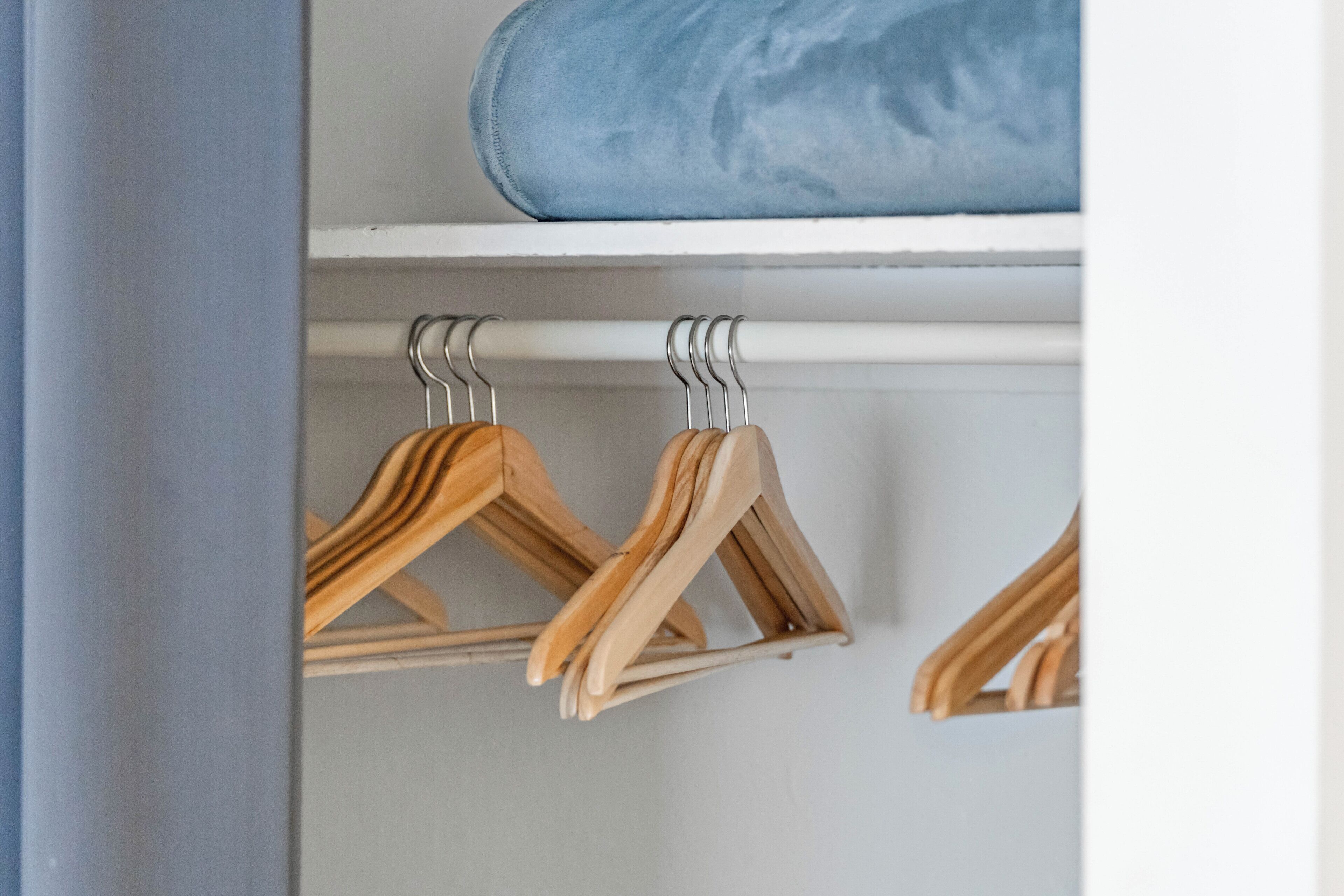 Een kast met houten kleerhangers en een blauwe opbergdoos.