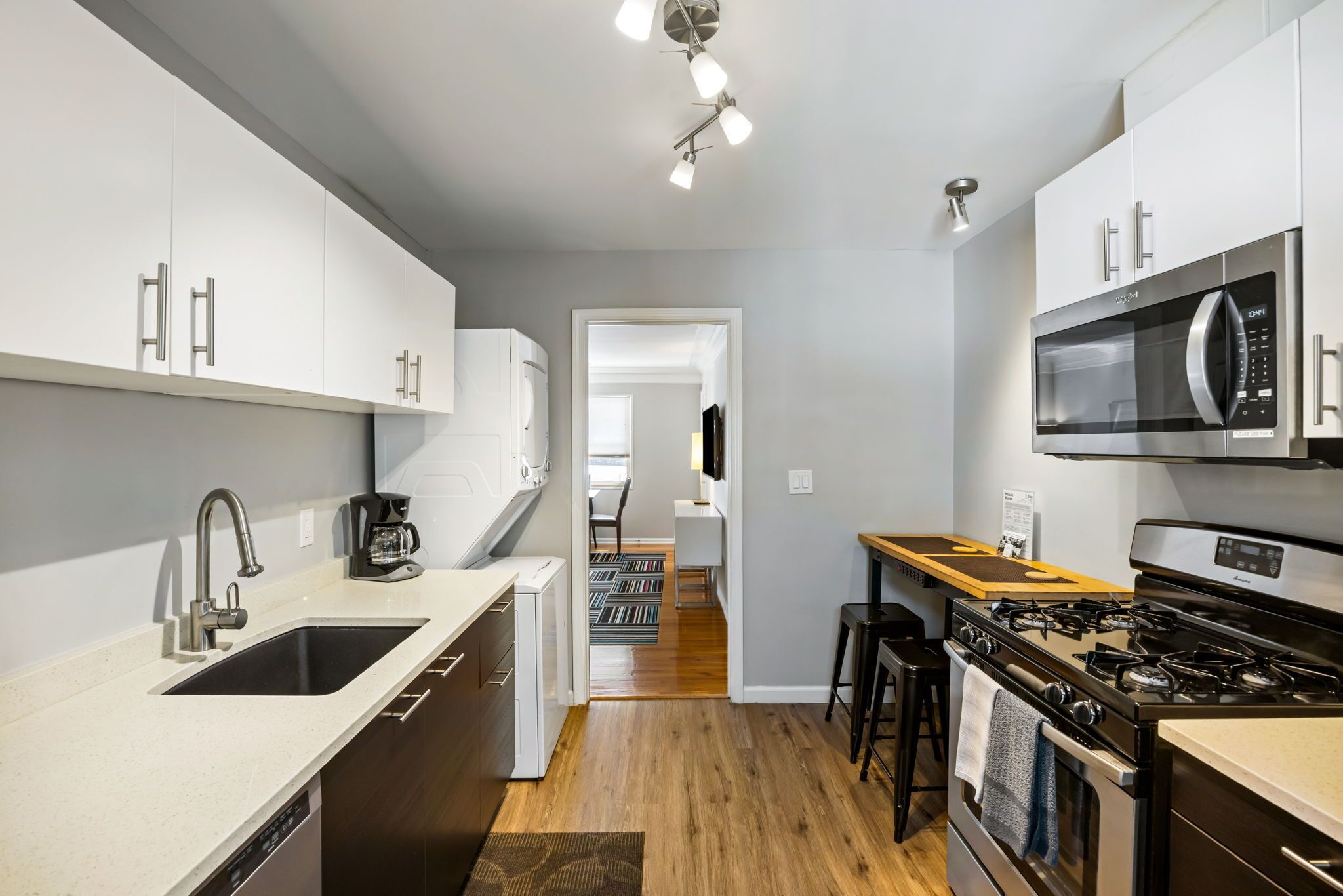 A modern kitchen with white cabinets, a stainless steel microwave, a gas stove, and a dishwasher.