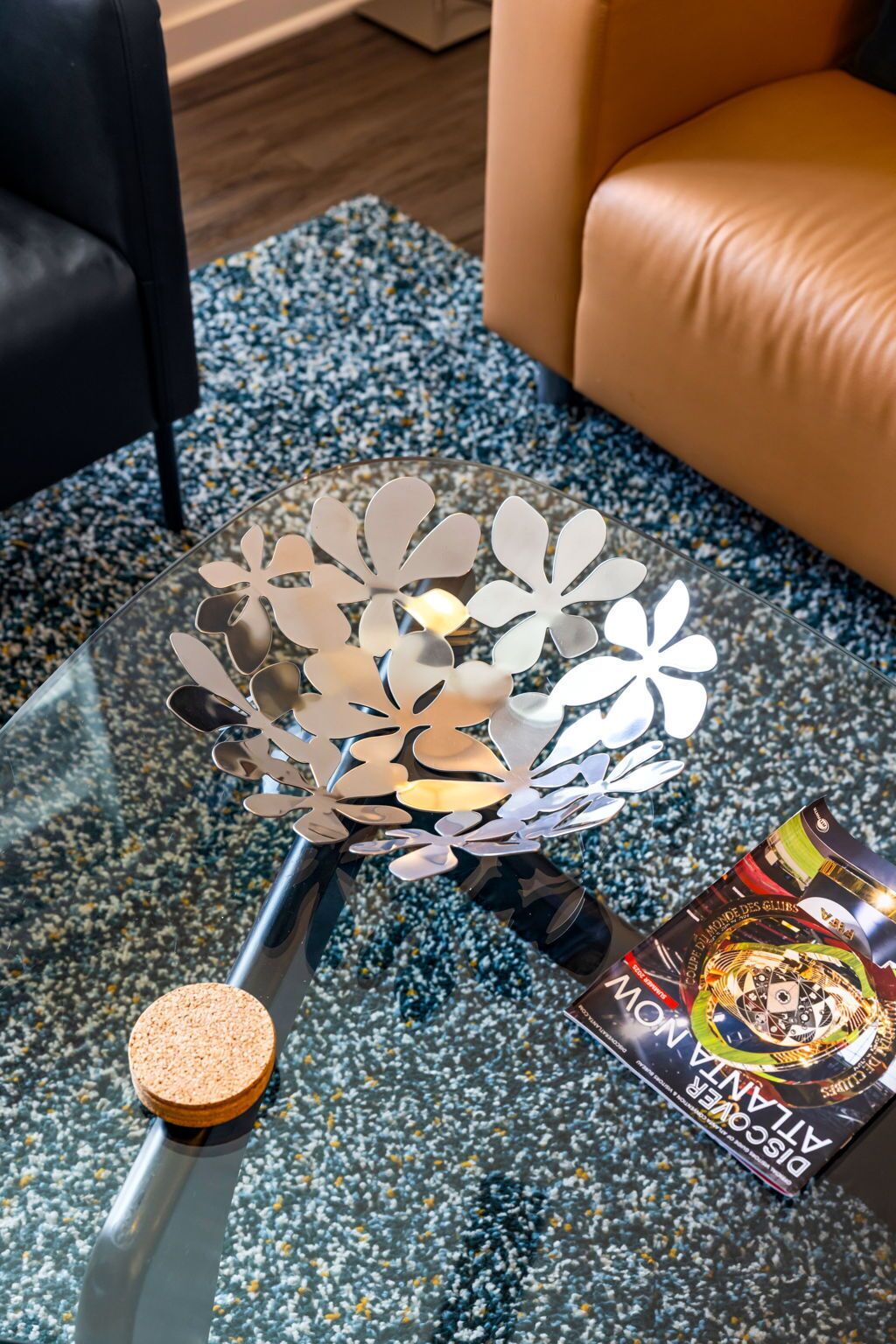 A glass table with a decorative metal piece and a bottle of wine.
