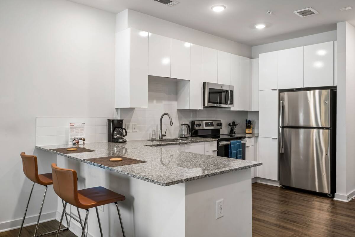 A modern kitchen with white cabinets, stainless steel appliances, and a granite countertop.