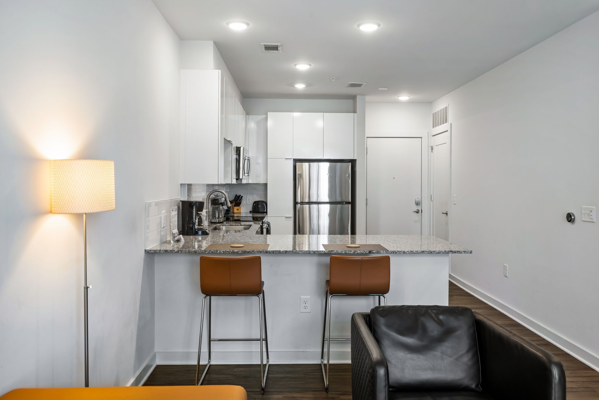 A modern kitchen with white cabinets, stainless steel appliances, and a central island with bar stools.