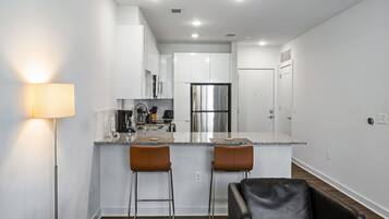 A modern kitchen with white cabinets, stainless steel appliances, and a central island with bar stools.