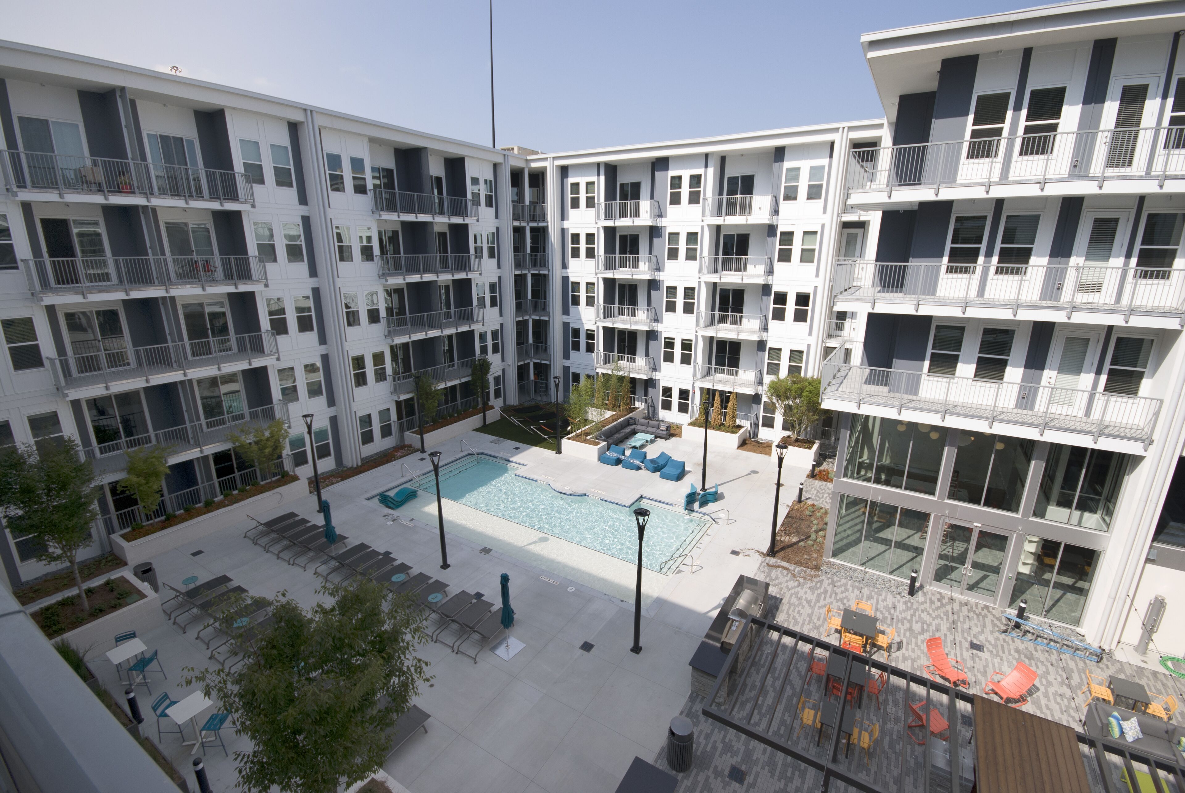 Un edificio residencial de varios pisos con balcones, un patio central con piscina y zonas de estar al aire libre.