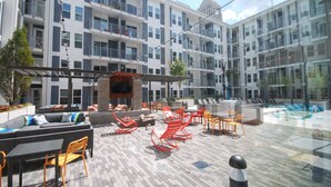 Una terraza en la azotea con mobiliario exterior, una zona de barbacoa y vistas del exterior del edificio.
