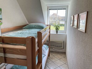 A small, well-lit room with a bunk bed, a radiator, a window with a view of the outside, and a potted plant. - Gollwitzer Park (Insel Poel) by Interhome (Gollwitz (Insel Poel))