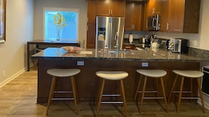 Una cocina moderna con armarios de madera, electrodomésticos de acero inoxidable y encimera de granito.