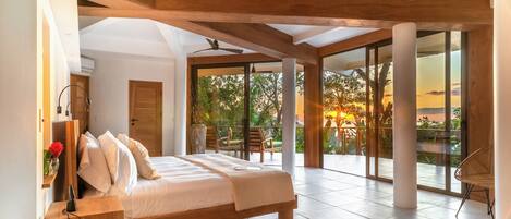 A spacious bedroom with a large bed, a desk, and a view of the outdoors.