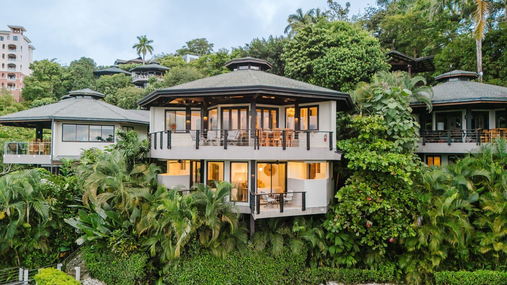 Un resort a più piani con un edificio centrale dotato di balconi, immerso in una rigogliosa vegetazione tropicale.