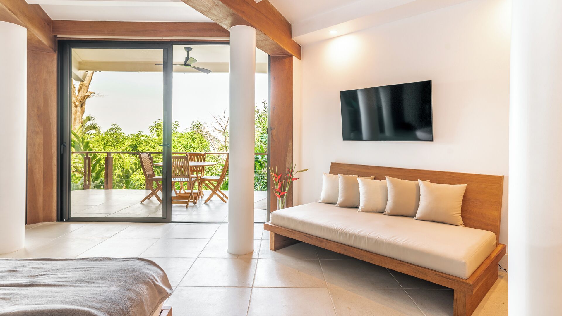 Une chambre d’hôtel moderne dotée d’un grand lit, d’un canapé, d’une télévision et d’un balcon avec une table et des chaises.
